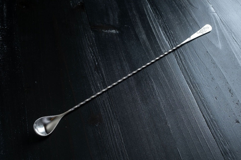 Silver cocktail spoon on a dark textured surface