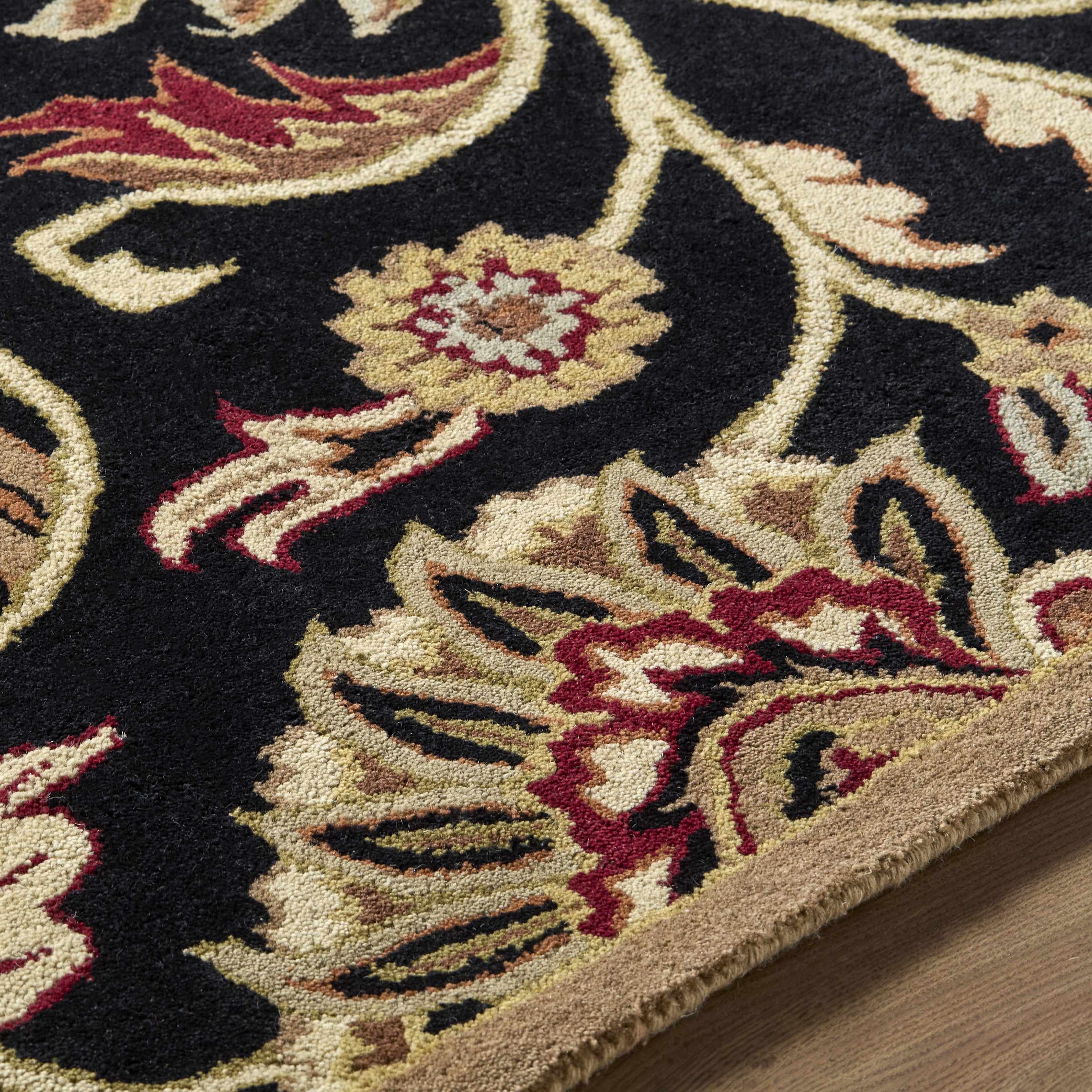 Close-up of an ornate floral rug with intricate patterns on a wooden floor.