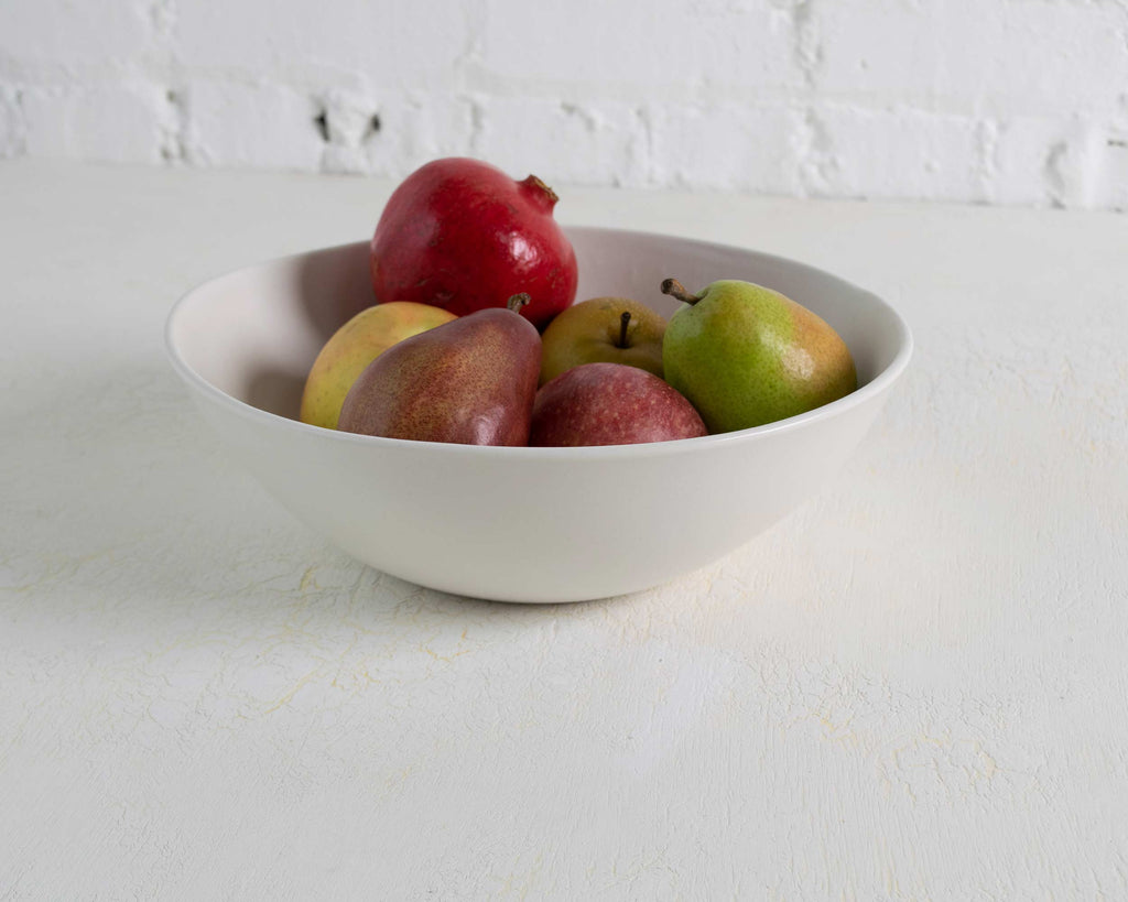 White bowl with apples on a white surface