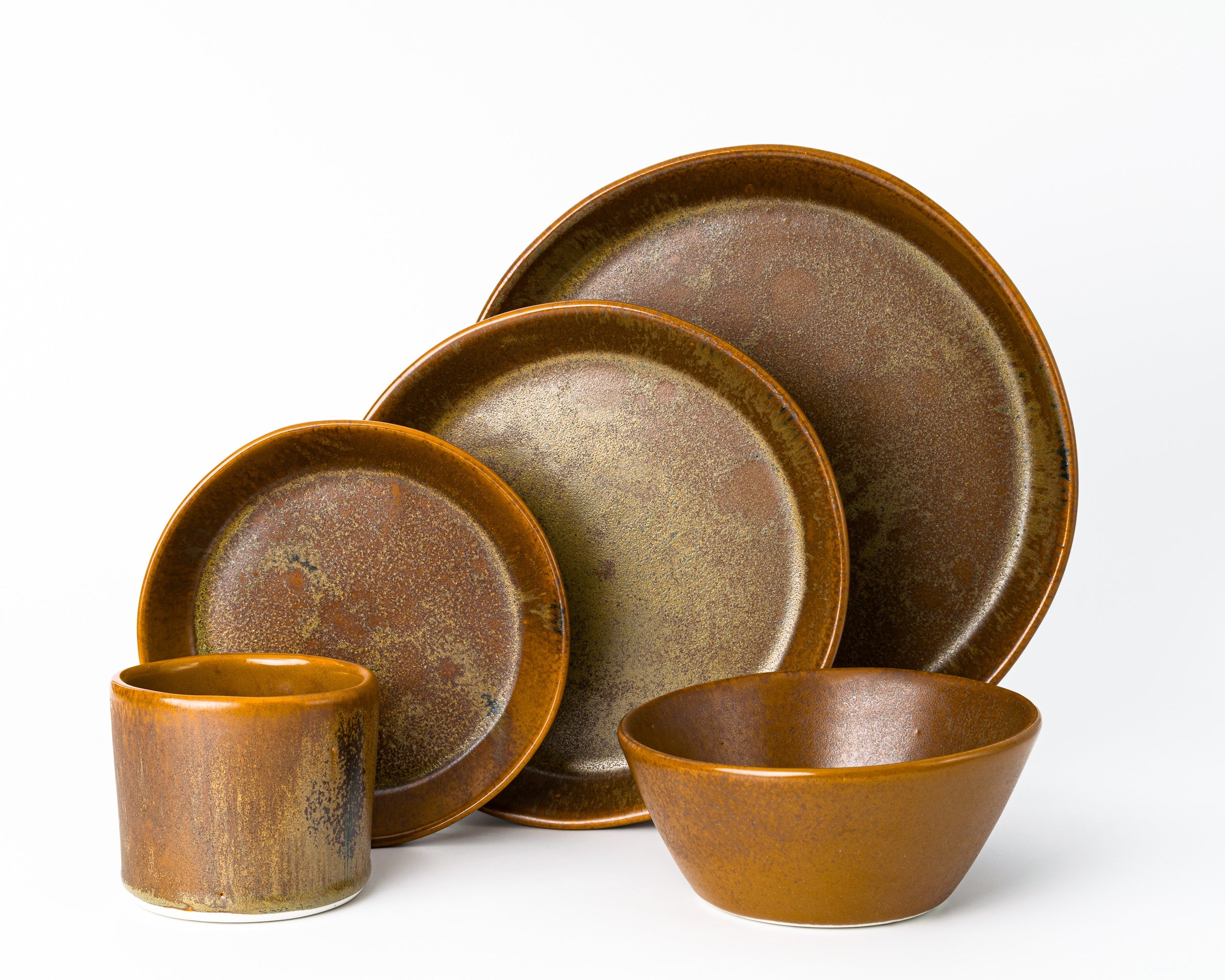 Set of brown ceramic dishes including plates and a cup on a white background