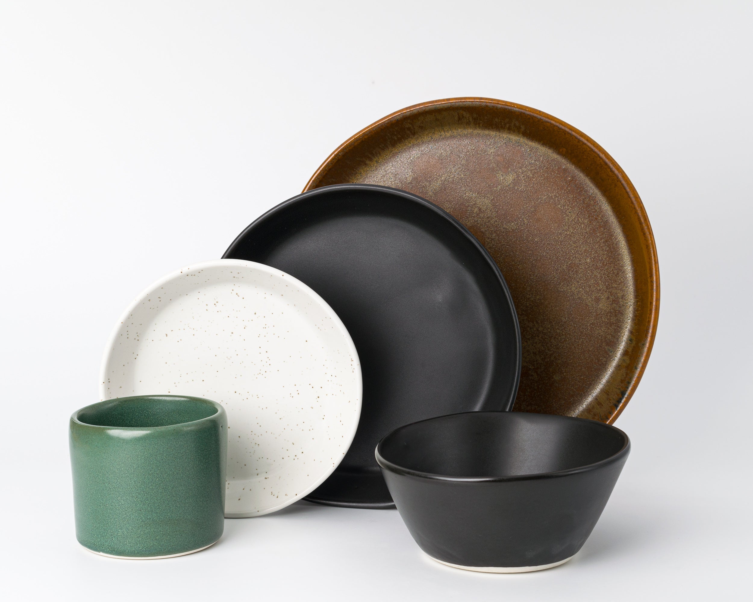 Set of ceramic dishes including a mug, bowl, and plates on a white background