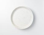Speckled ceramic plate on a light gray background