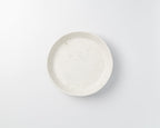 Speckled ceramic plate on a light gray background