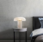 Modern table lamp on a side table next to a bed with a gray wall background