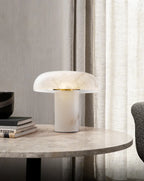 Modern table lamp on a marble surface with books and a curtain in the background