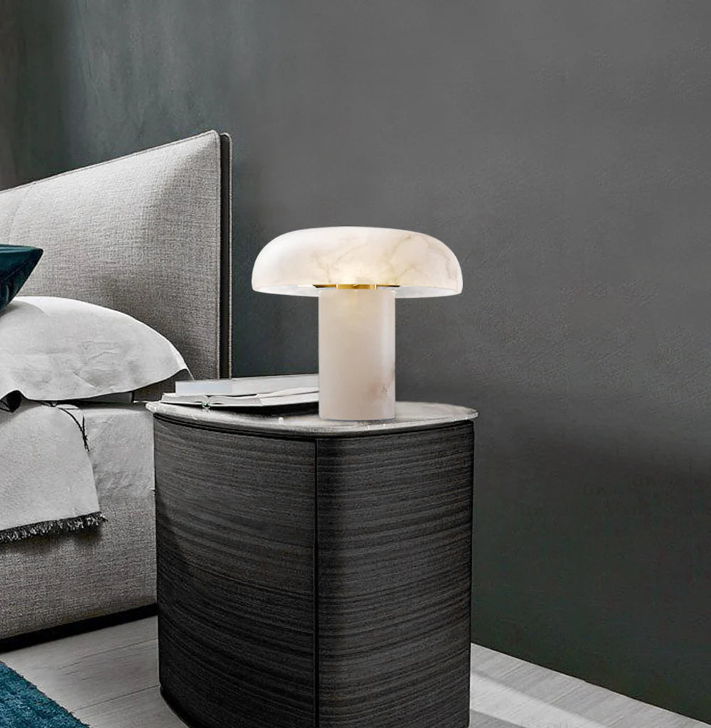 Modern table lamp on a bedside table next to a bed with gray bedding.