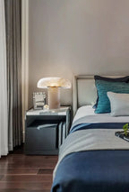 Modern bedroom with a bed, nightstand, and lamp.