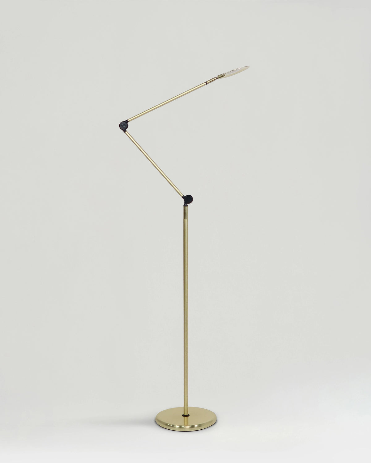 Gold floor lamp with adjustable arm on a light gray background