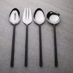 Set of black-handled silver spoons and fork on a gray surface