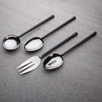 Set of black-handled silver spoons and fork on a gray surface