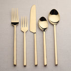 Set of gold cutlery including forks and spoons on a textured surface