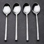 Four silver spoons on a dark gray background