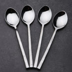 Four silver spoons on a dark gray background