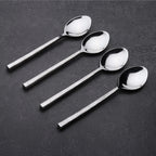 Four silver spoons arranged on a dark surface