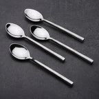 Set of four silver spoons on a dark surface
