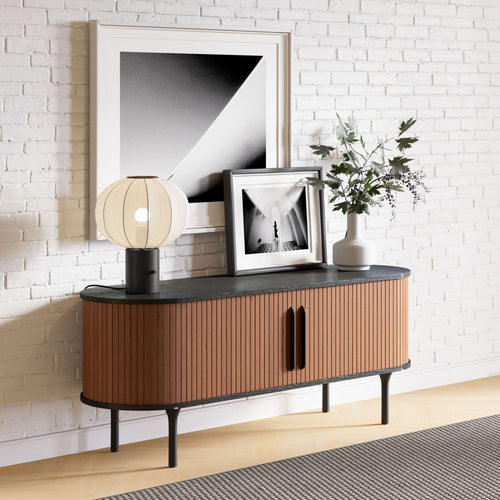 Wooden sideboard with decorative items against a white brick wall