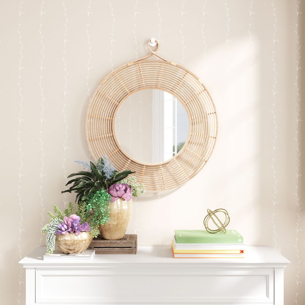 Round wicker mirror on a wall above a white console table with decorative items.
