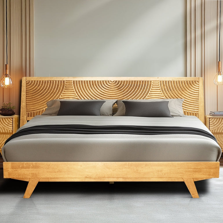 Wooden bed with decorative headboard and pillows in a room setting.