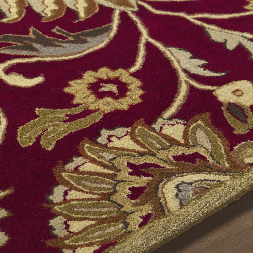 Close-up of a red floral patterned rug with gold and beige accents.