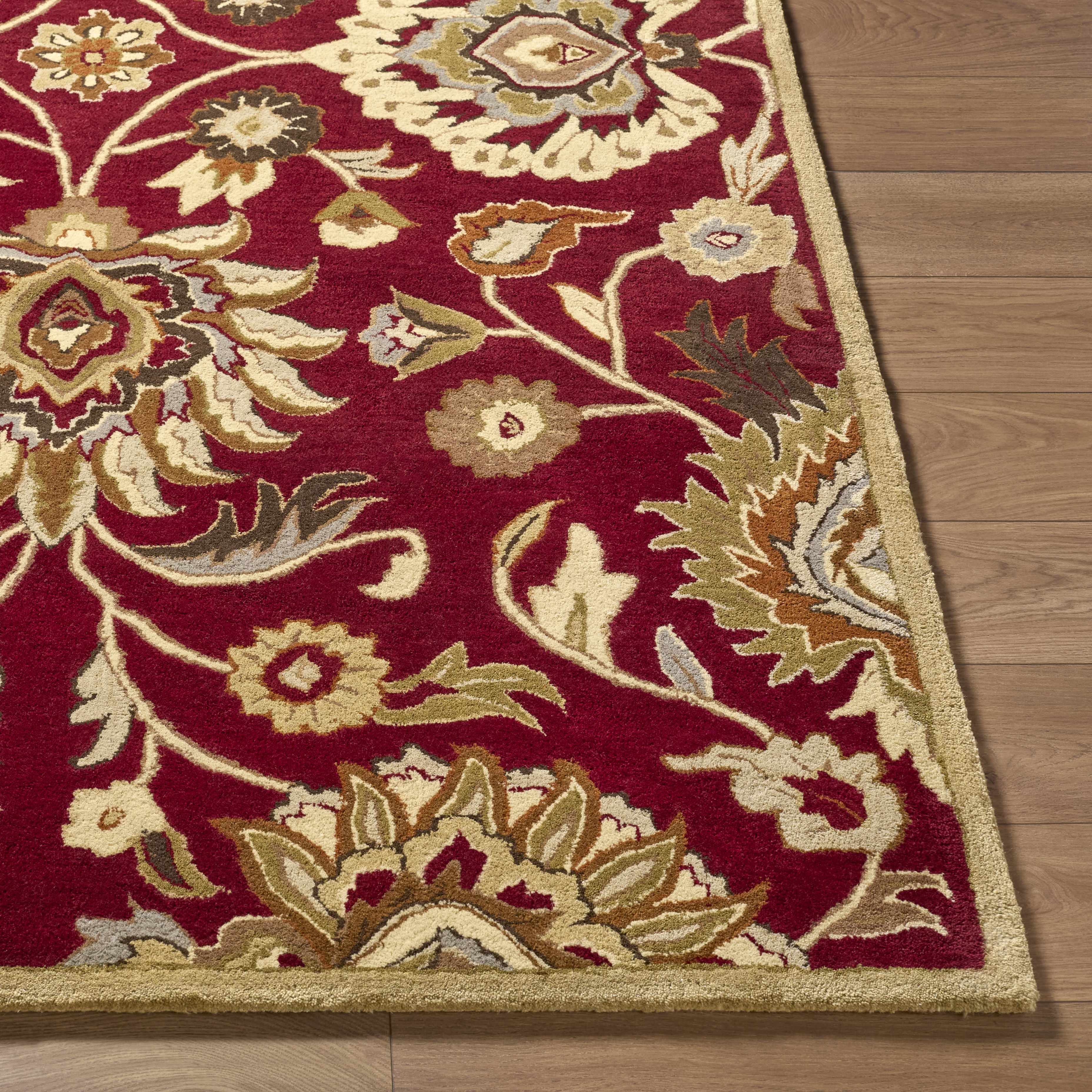 Decorative red and beige floral rug on a wooden floor