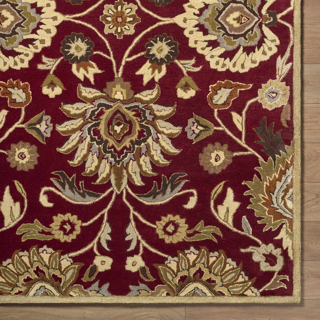 Close-up of a red floral patterned rug on a wooden floor.