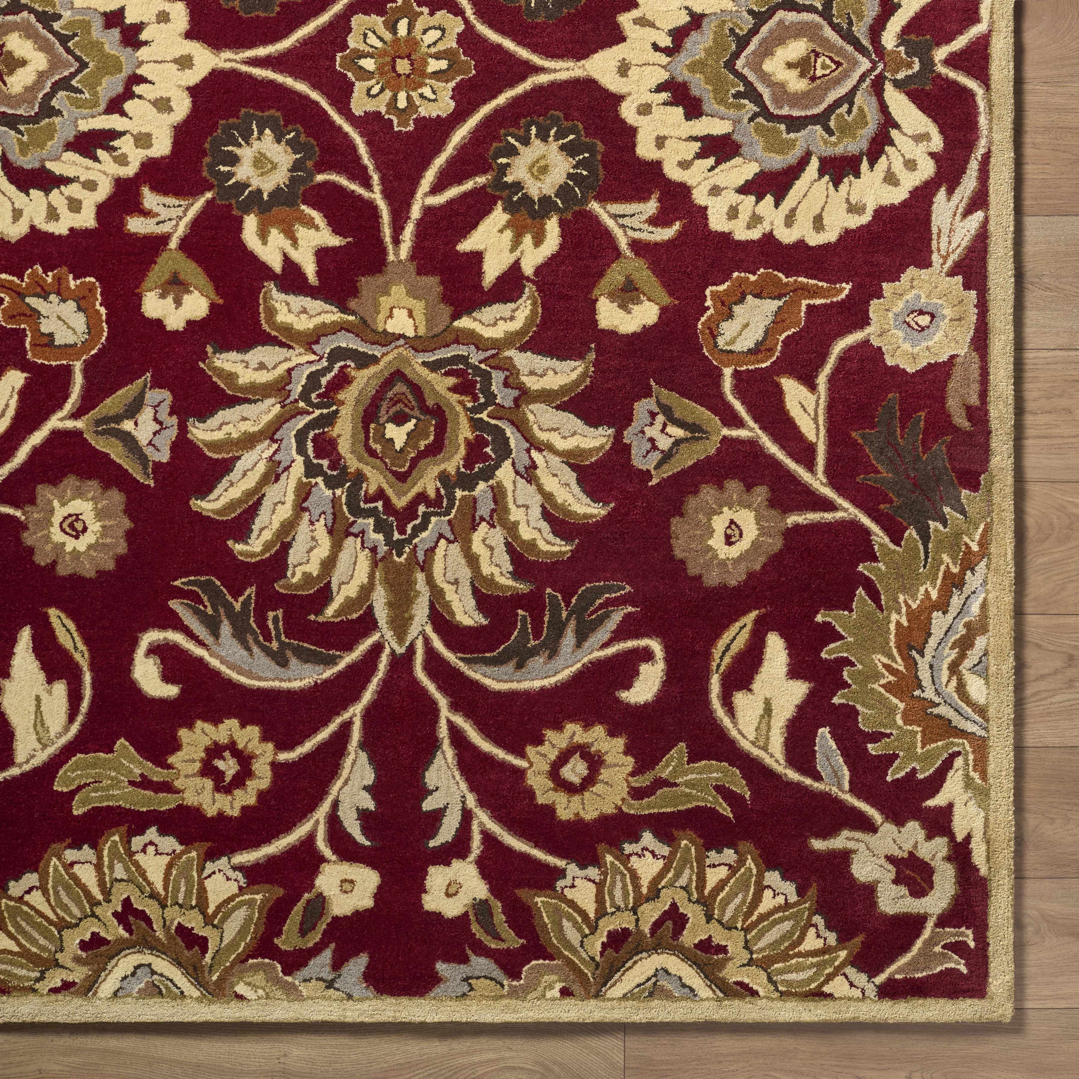 Close-up of a red floral patterned rug on a wooden floor.