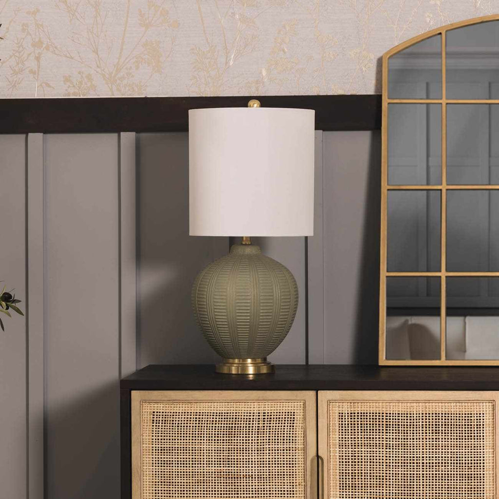 Decorative textured table lamp on a cabinet with a mirror and textured wall in the background