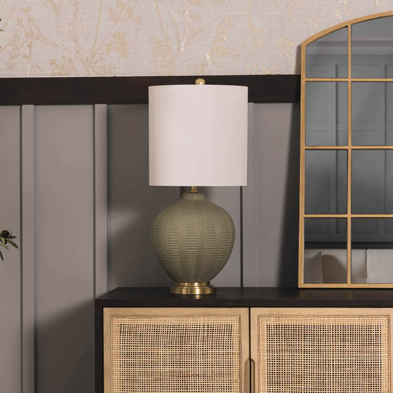 Decorative textured table lamp on a cabinet with a mirror and textured wall in the background