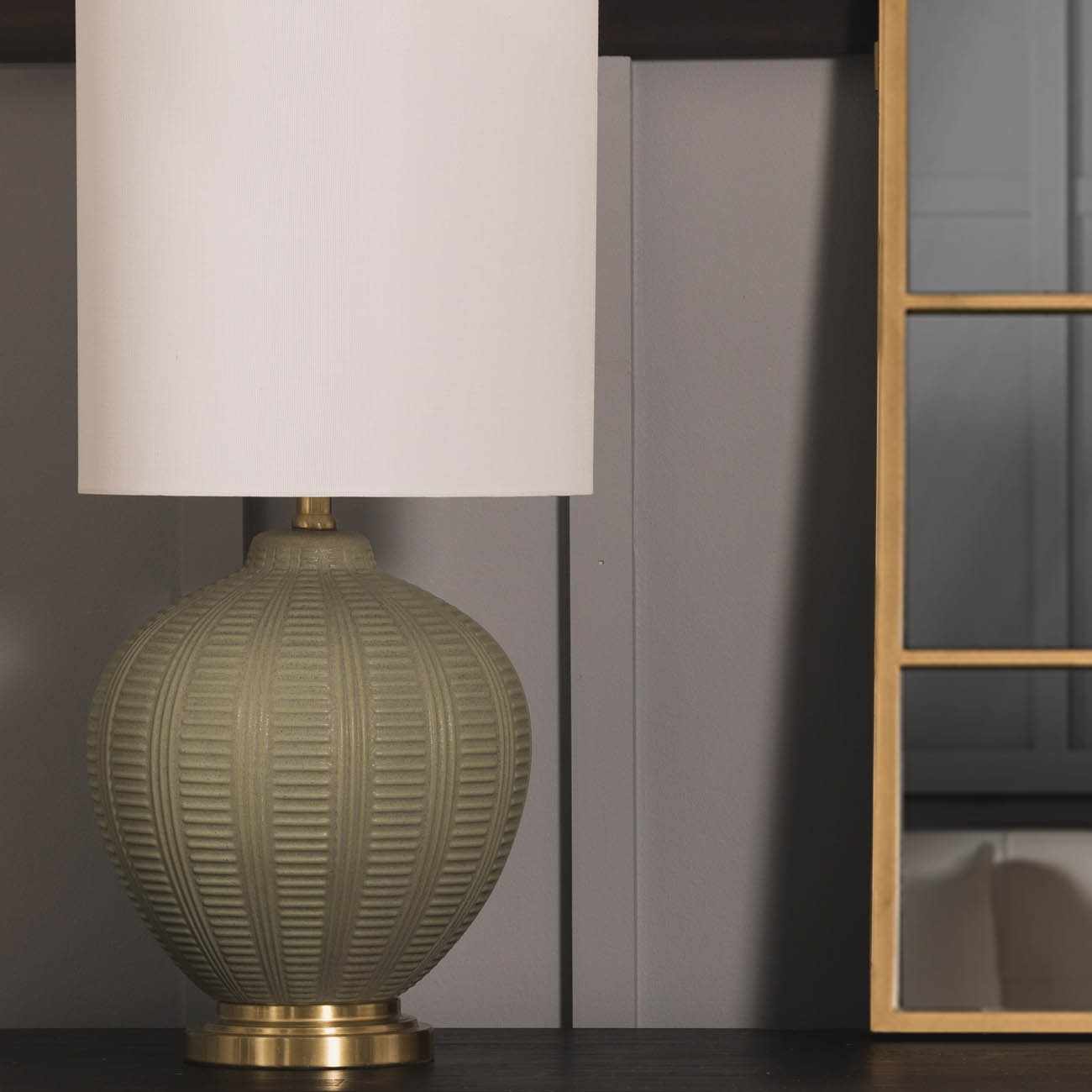 Green textured table lamp with a white shade on a dark surface.