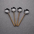 Four metal ladles with copper handles on a gray background