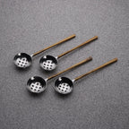 Four metal ladles with copper handles on a gray background