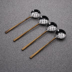 Set of four metal ladles with copper handles on a gray background