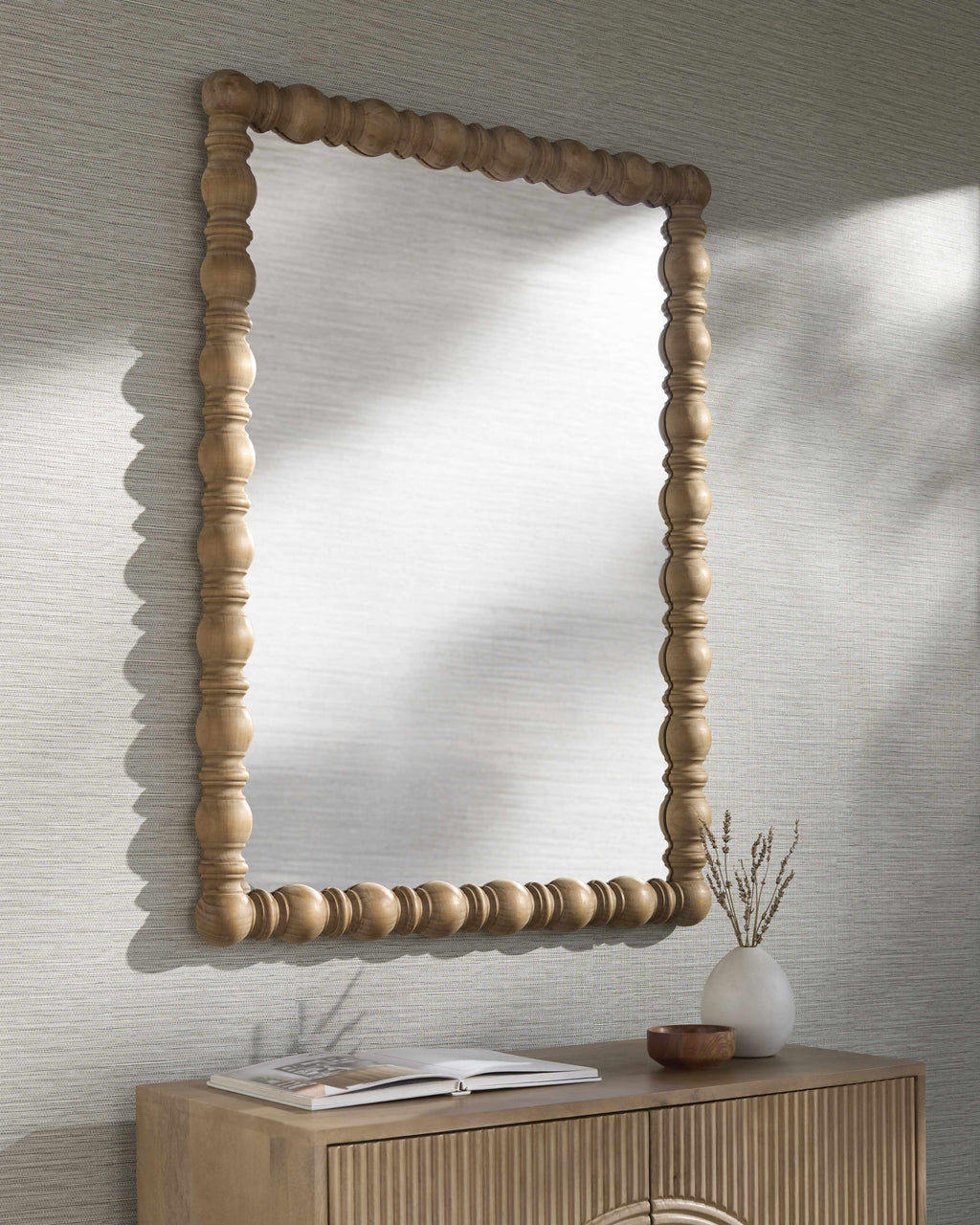 Wooden framed mirror on a wall with a textured finish