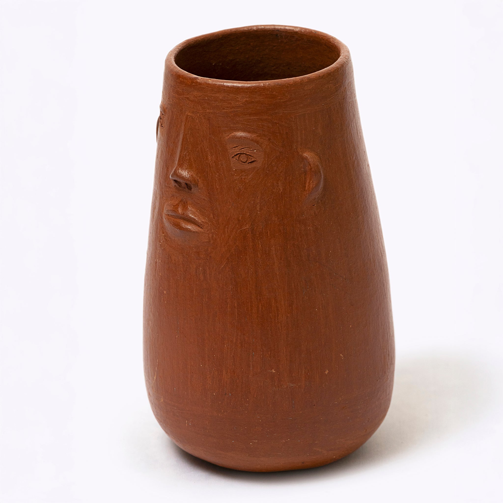 Brown ceramic vase with face design on a white background