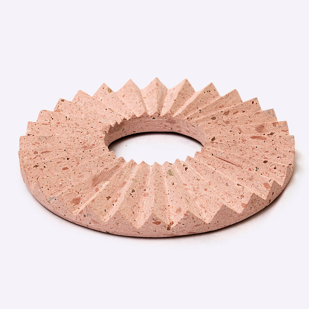 Pink stone with a textured, fan-like coaster on a white background