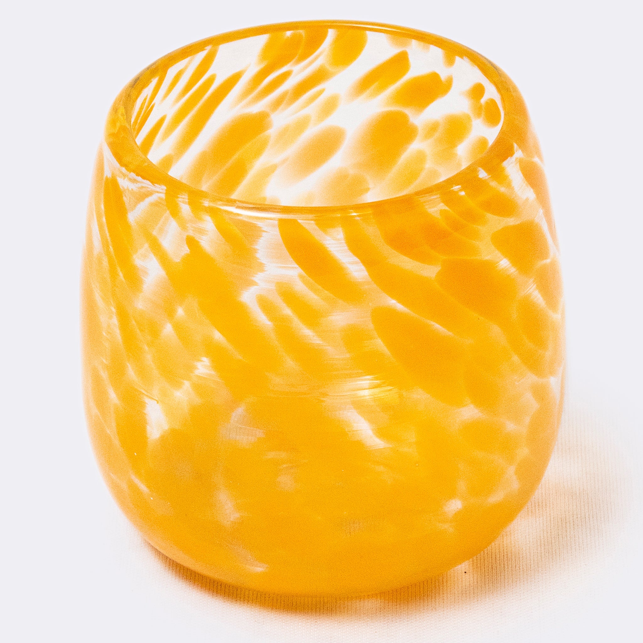 Yellow glass tumbler with textured surface on a white background