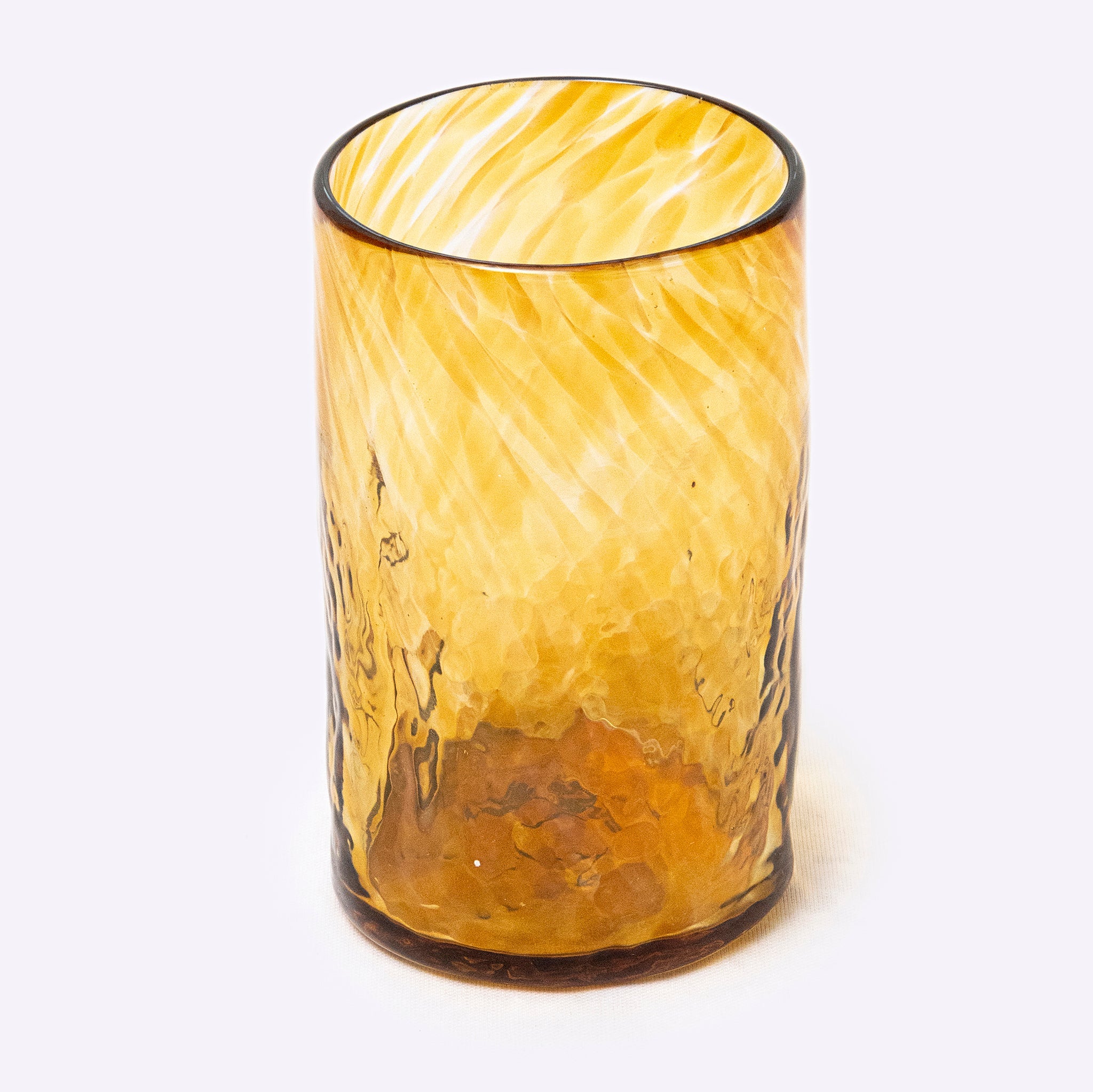 Yellow glass tumbler with textured surface on a white background