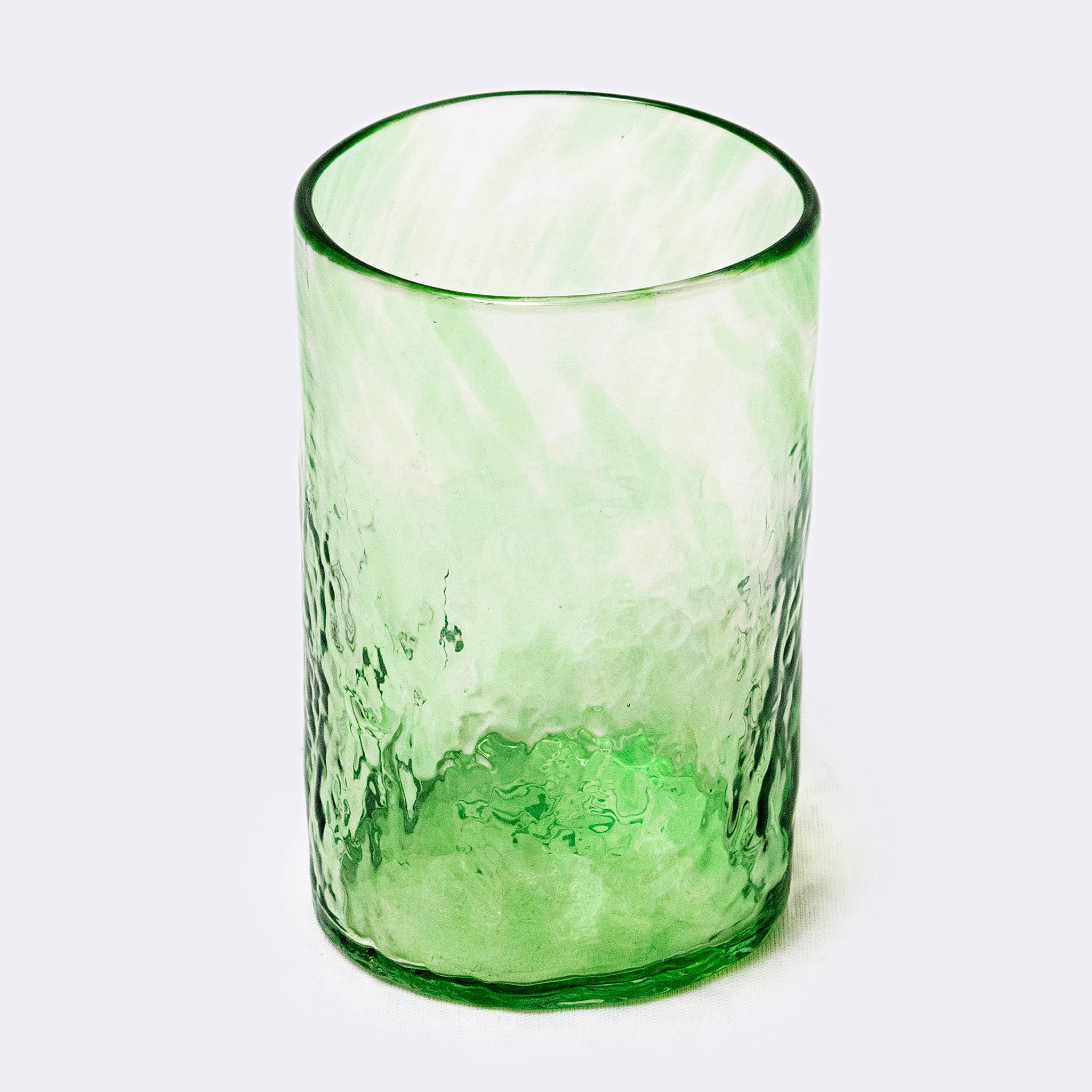 Green glass tumbler on a white background