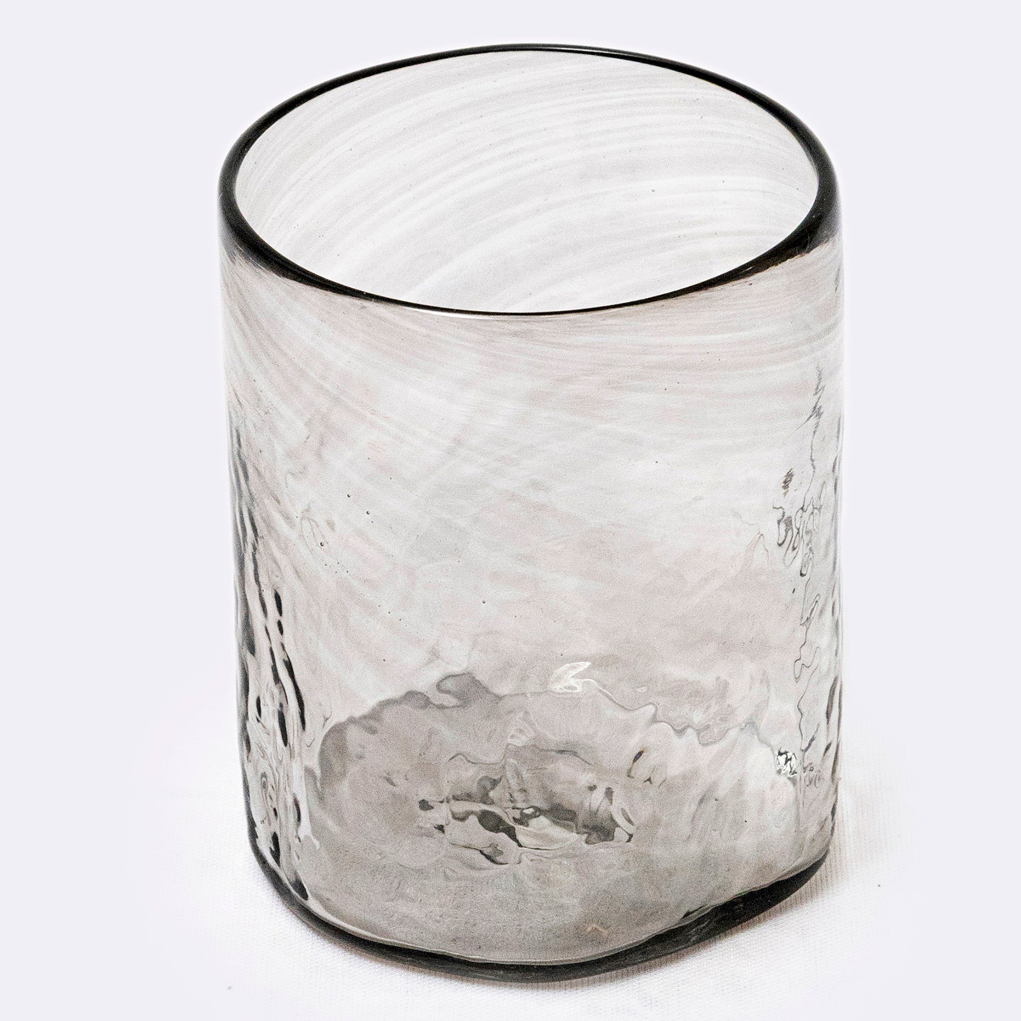 Clear grey glass tumbler with textured surface on a white background