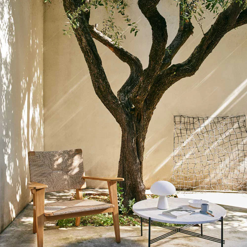 Outdoor setting with a wooden chair, table, and decorative elements under a tree.