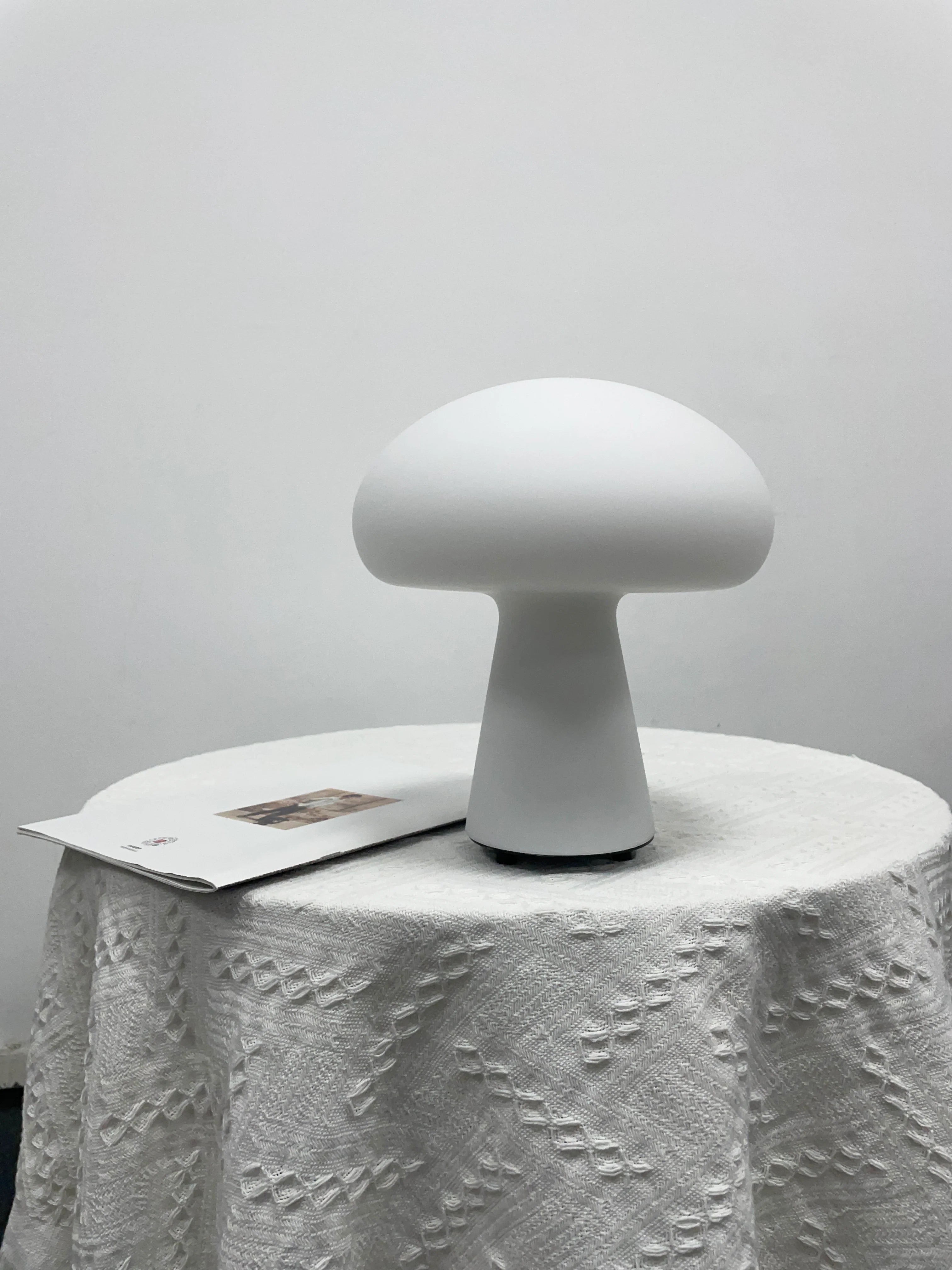 White mushroom-shaped lamp on a textured white surface with a light gray background