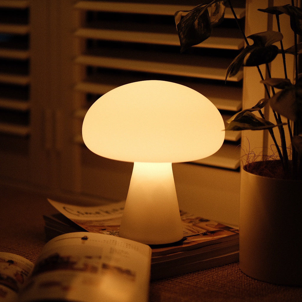 Mushroom-shaped lamp on a table with a plant and newspaper in the background
