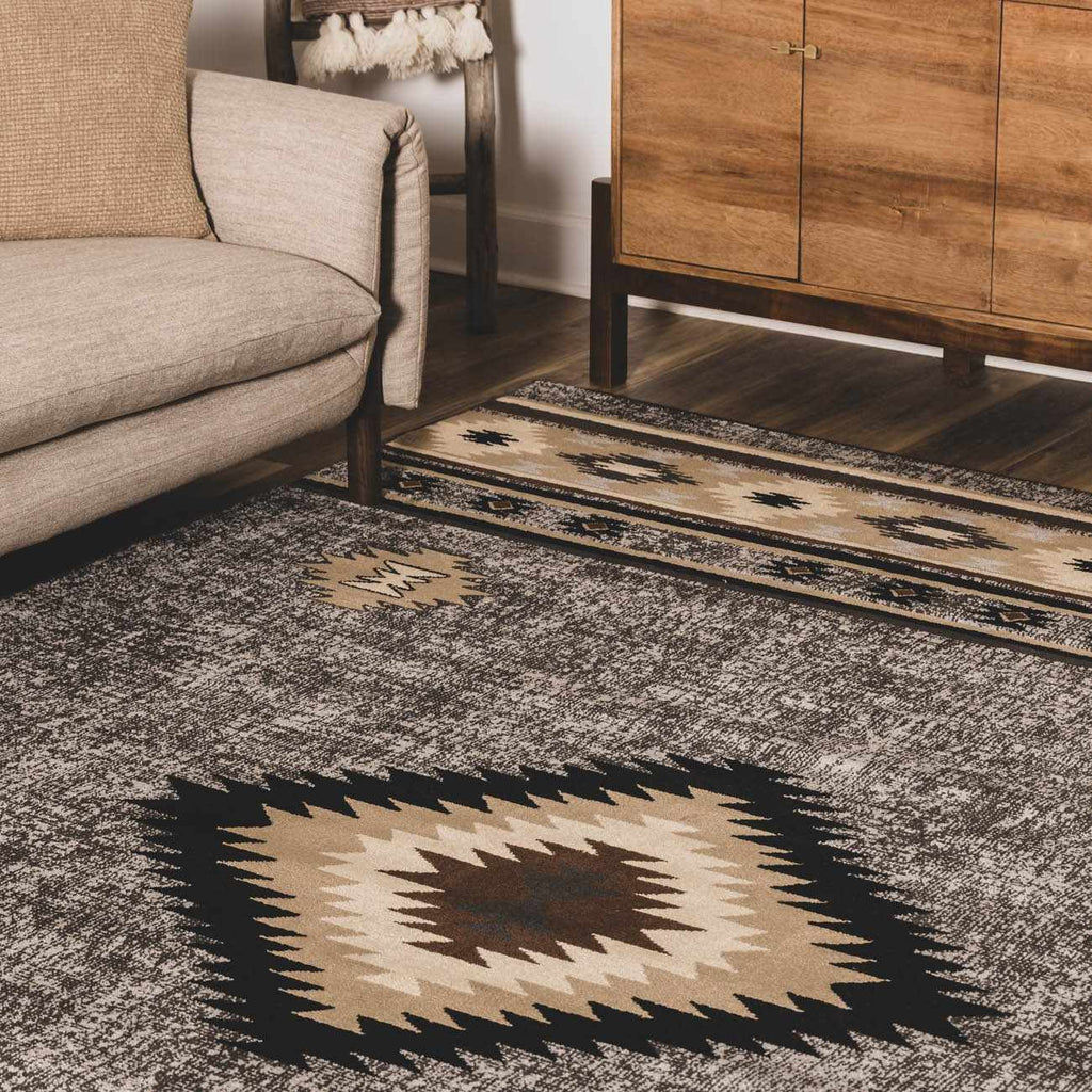 Patterned rug on a wooden floor with a beige sofa and wooden cabinet in the background.