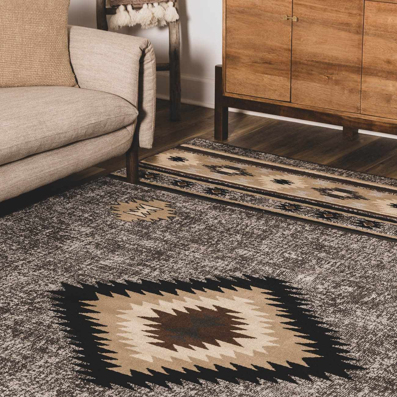 Patterned rug on a wooden floor with a beige sofa and wooden cabinet in the background.