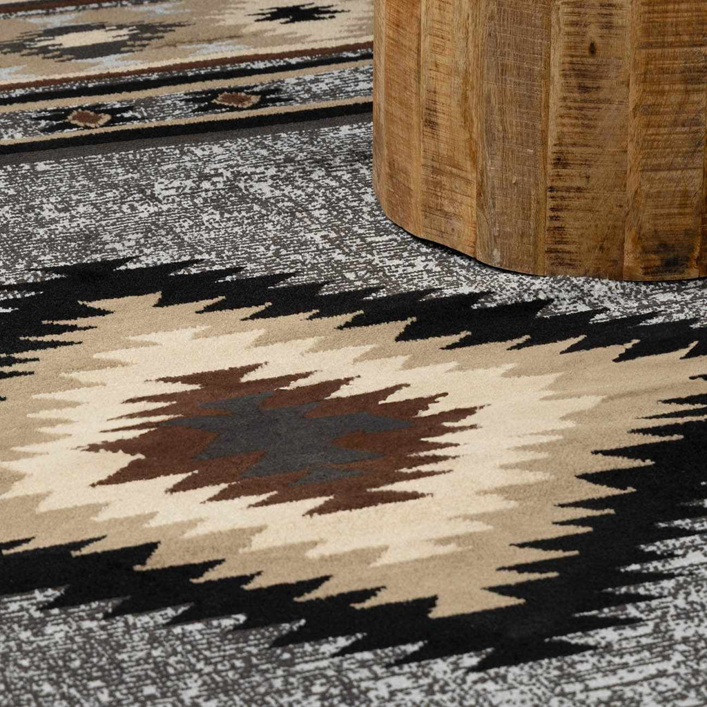 Close-up of a patterned rug with geometric design and a wooden stool.