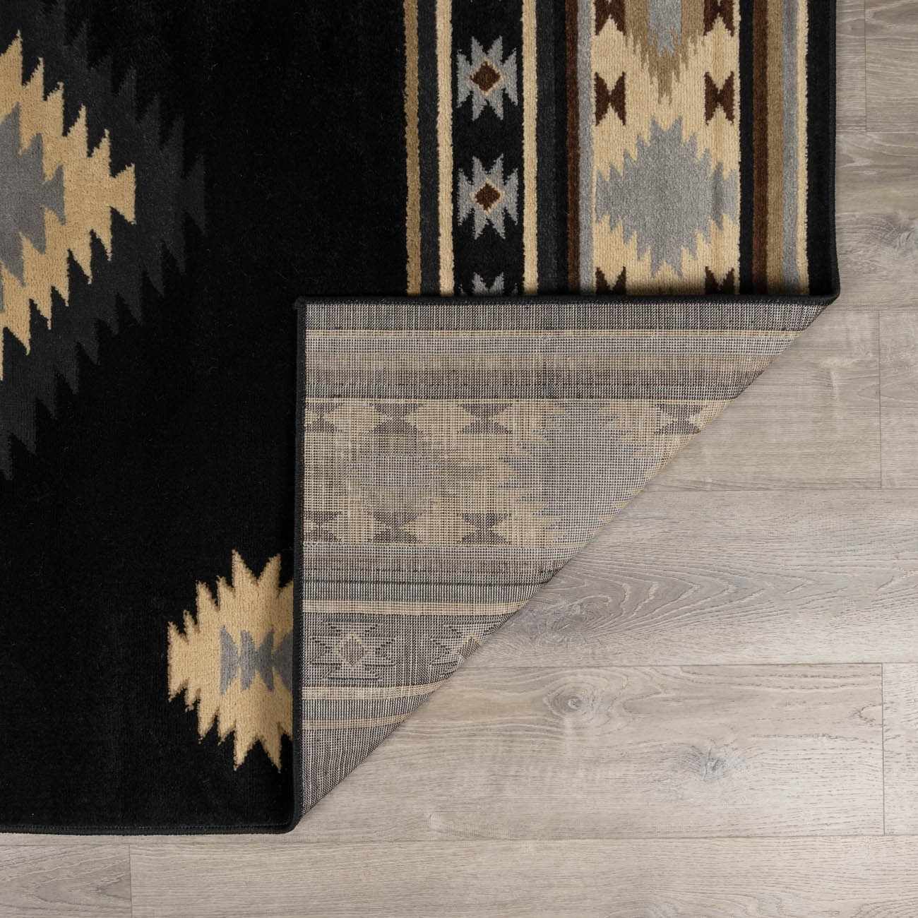 Close-up of a patterned rug with geometric designs on a wooden floor.