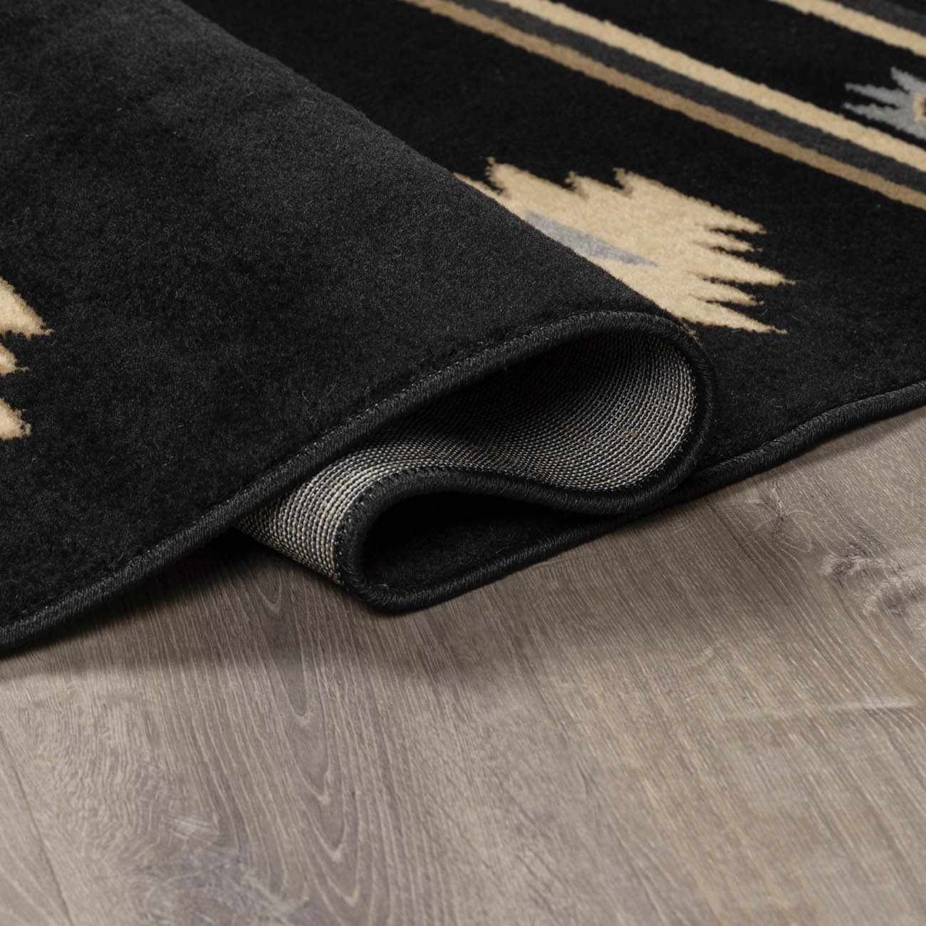 Black rug with geometric patterns on a wooden floor