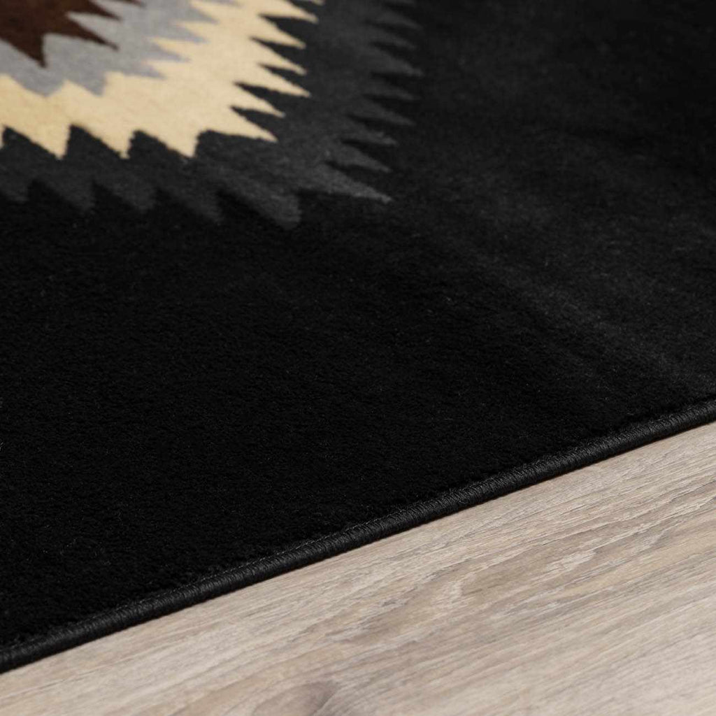 Black rug with geometric pattern on a wooden floor