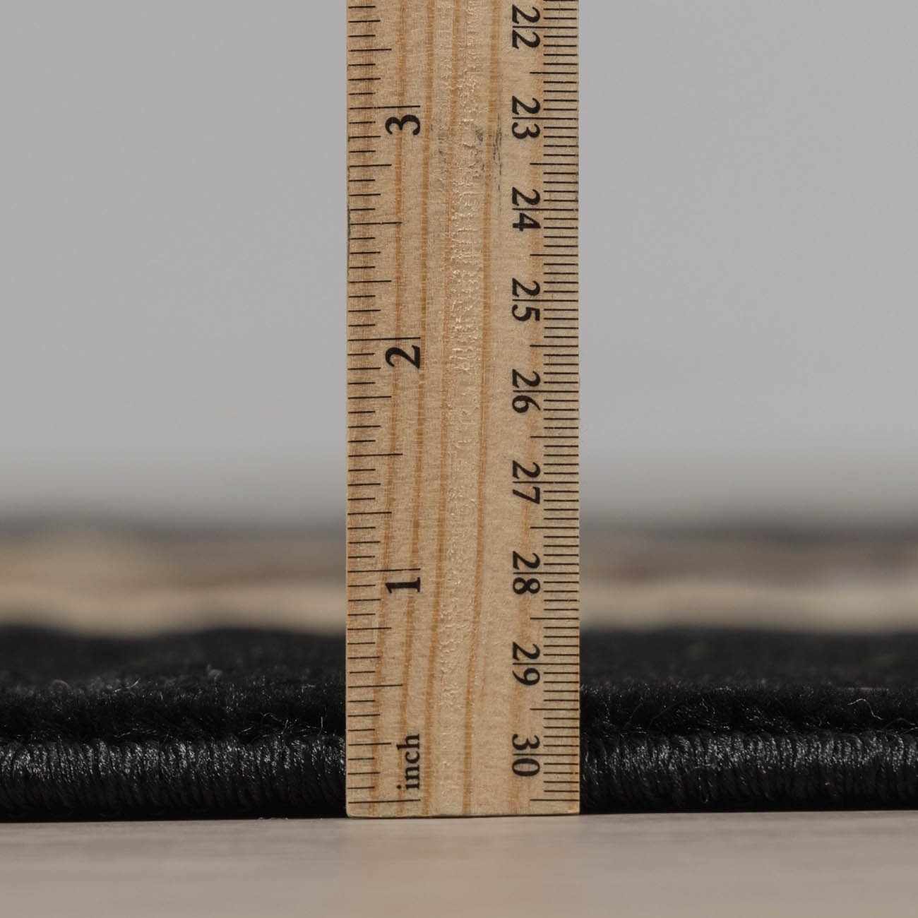 Wooden ruler measuring black fabric with a blurred background