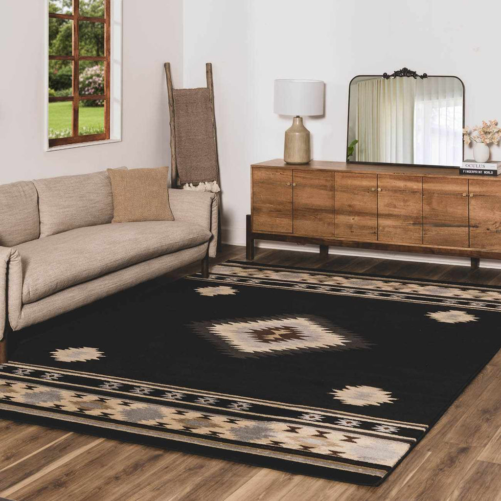 Living room with a black patterned rug, beige sofa, wooden sideboard, and decorative elements.